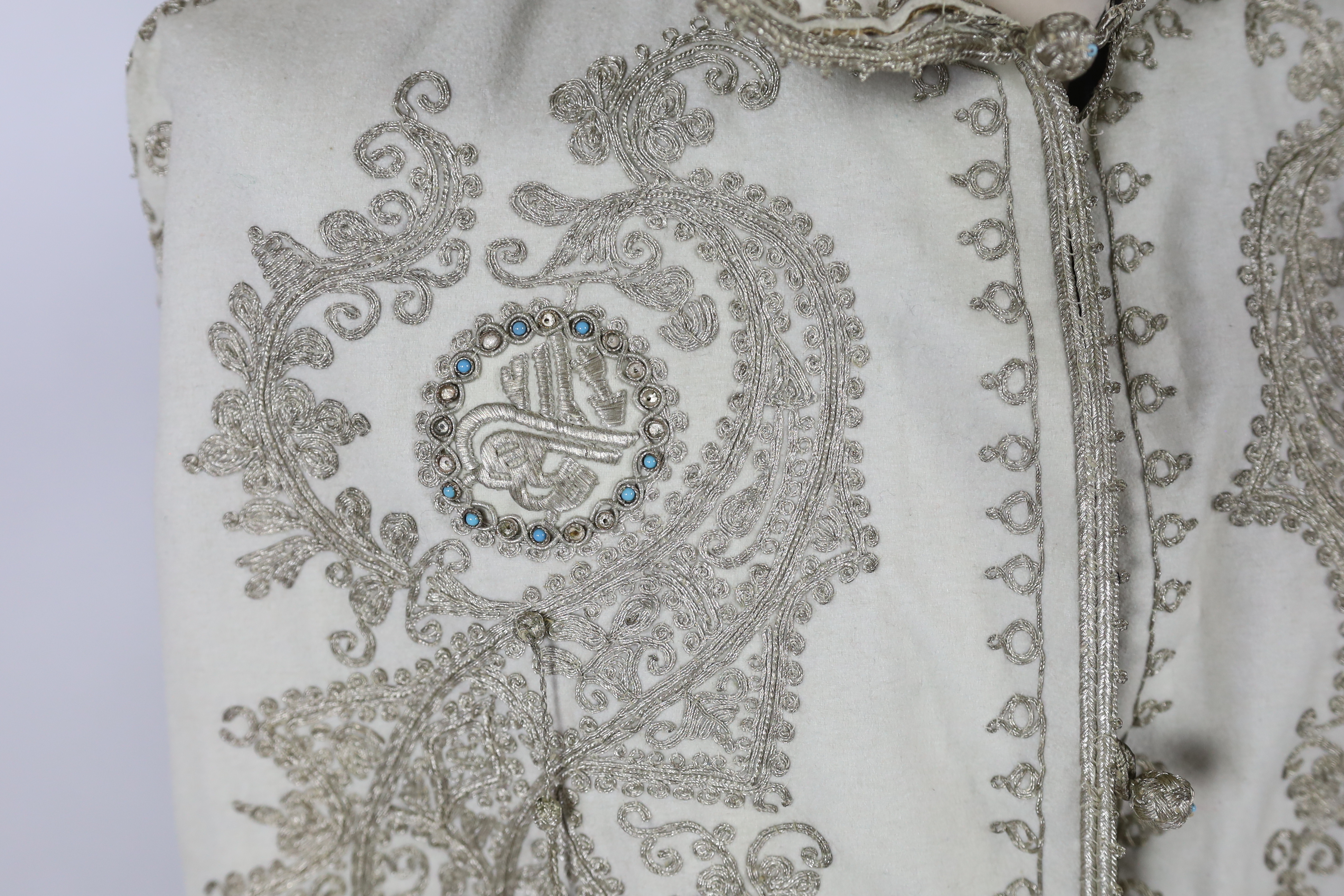 A 19th century Indian fine cream wool embroidered cape, probably made for the European market, embroidered in panels of silver metallic thread in an ornate vertical design with turquoise embellishments and lined in black